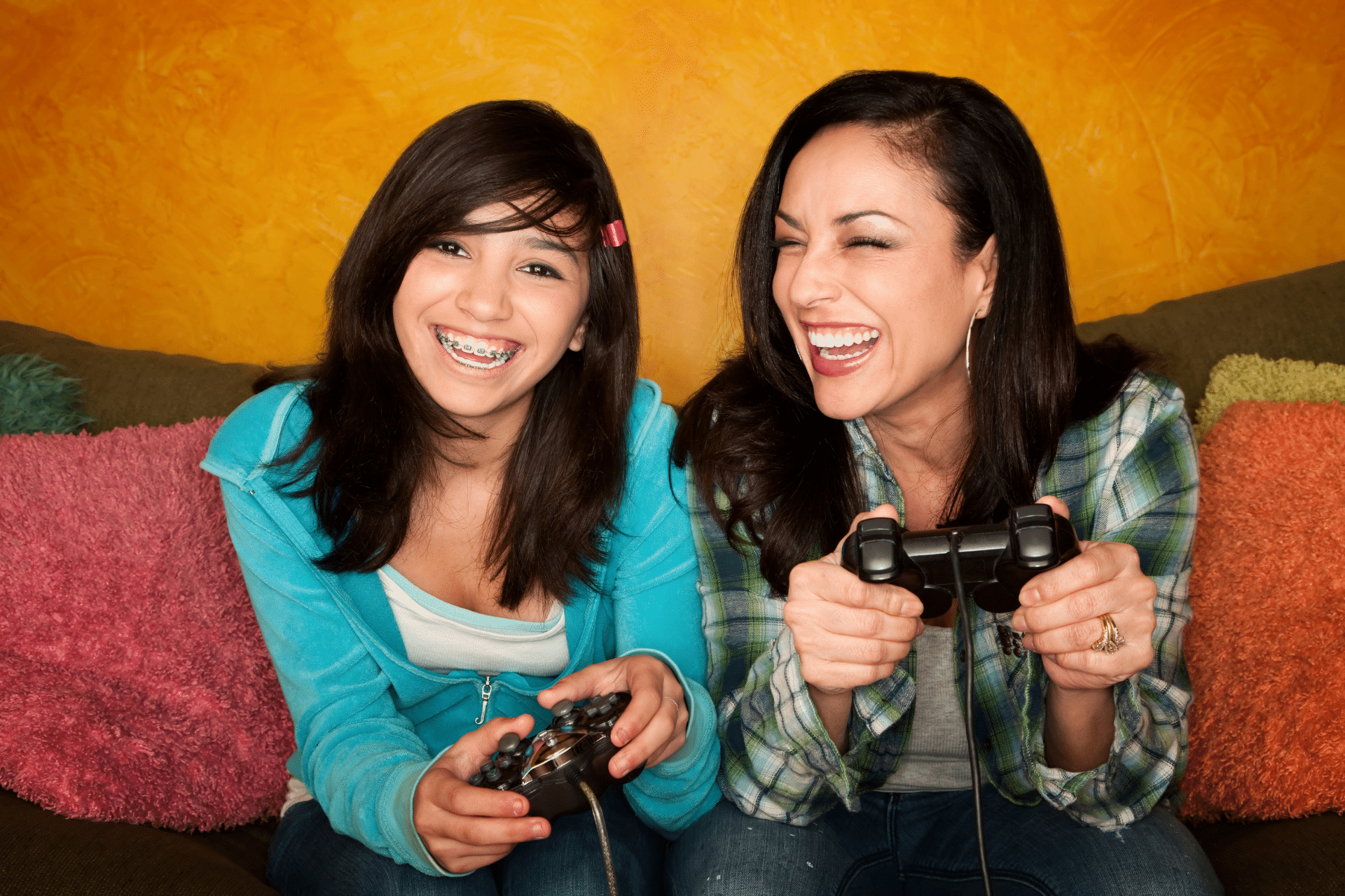 Teen wearing braces and an adult smiling while playing video games together