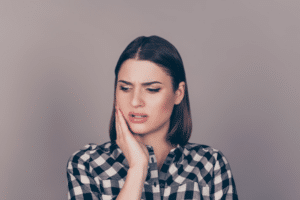 Woman holding her cheek with a concerned expression