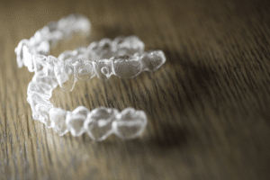 Clear orthodontic aligners resting on a wooden surface